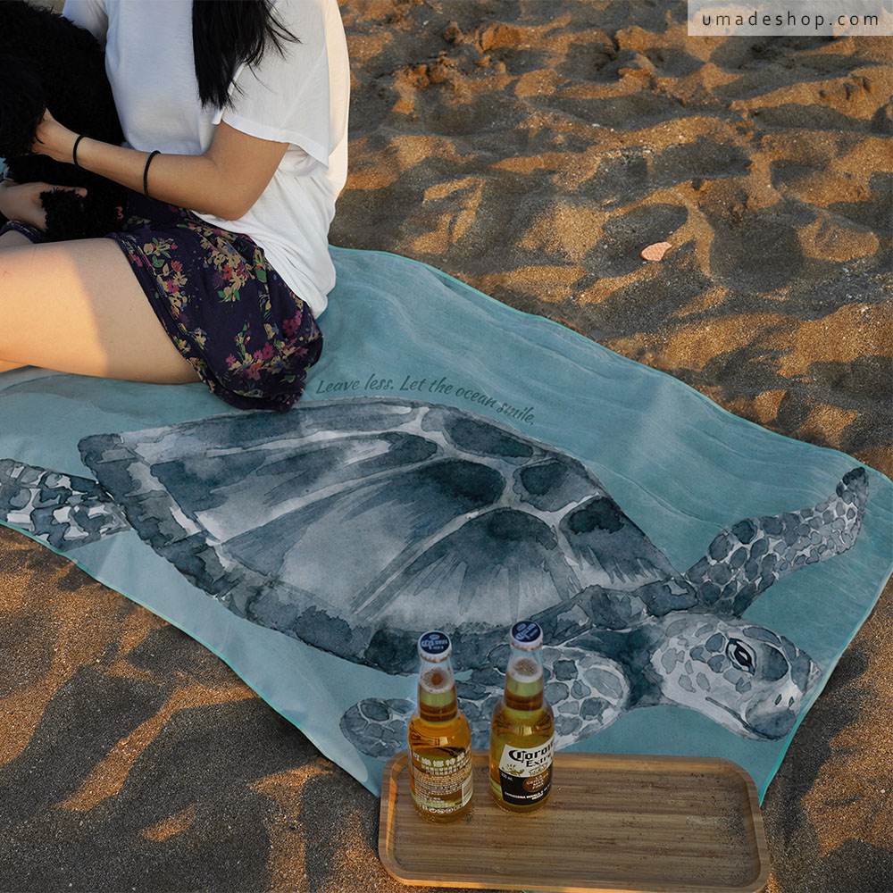 Umade 海洋微笑系列萬用快乾巾海龜款,在海邊展示L尺寸。SUP、游泳、衝浪、潛水、海邊日光浴都適合,也能作為海灘巾、旅行毛巾、健身毛巾、浴巾與擦頭巾,一巾多用,出遊居家生活都實用。