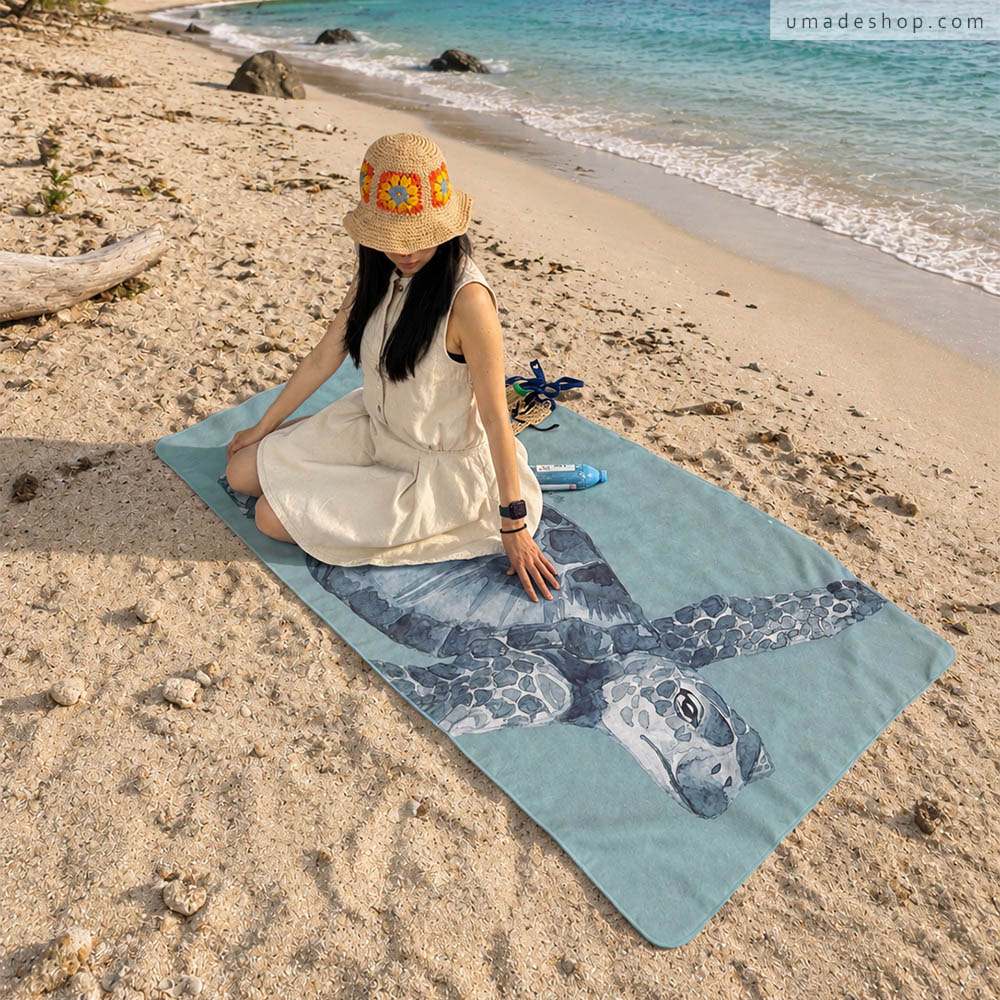 Umade 海洋微笑系列萬用快乾巾海龜款，在海邊展示Ｌ尺寸。SUP、游泳、衝浪、潛水、海邊日光浴都適合，也能作為海灘巾、旅行毛巾、健身毛巾、浴巾與擦頭巾，一巾多用，出遊居家生活都實用。