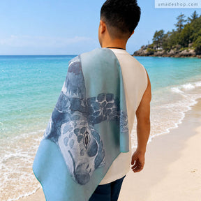 Umade 海洋微笑系列萬用快乾巾海龜款，站在沙灘上展示海龜圖案快乾巾，適合海邊玩水使用。SUP、游泳、衝浪、潛水、日光浴都適合，